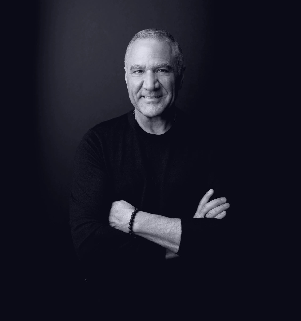 Black and white portrait of Christian Drapeau with arms crossed against a dark background