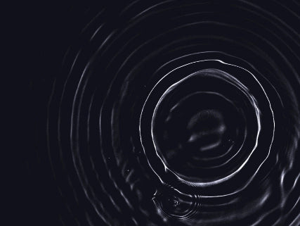 Black and white circular pattern resembling water ripples on a dark background